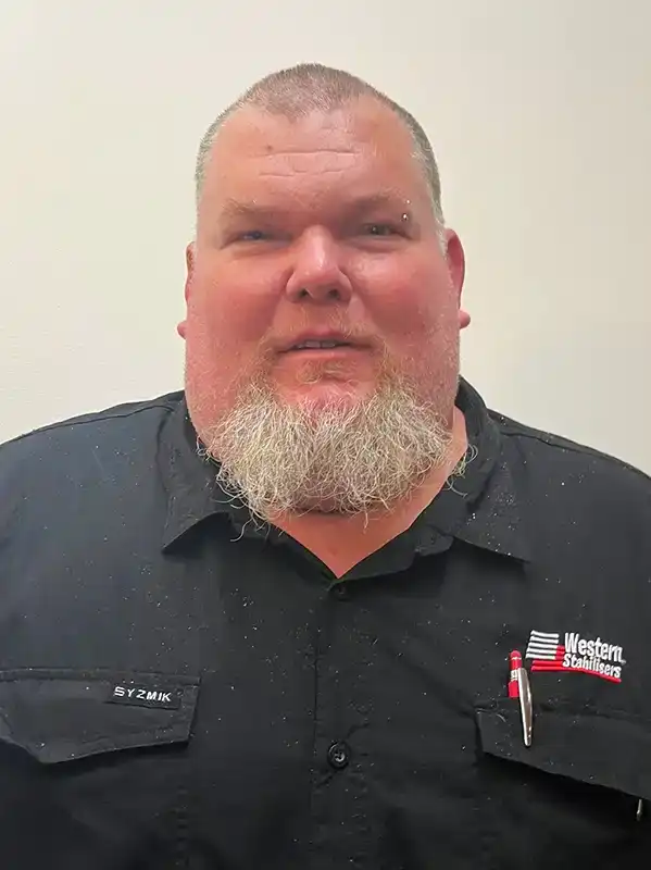 A man with a white beard wearing a black "Western Stabilizers" shirt stands in front of a plain white background.